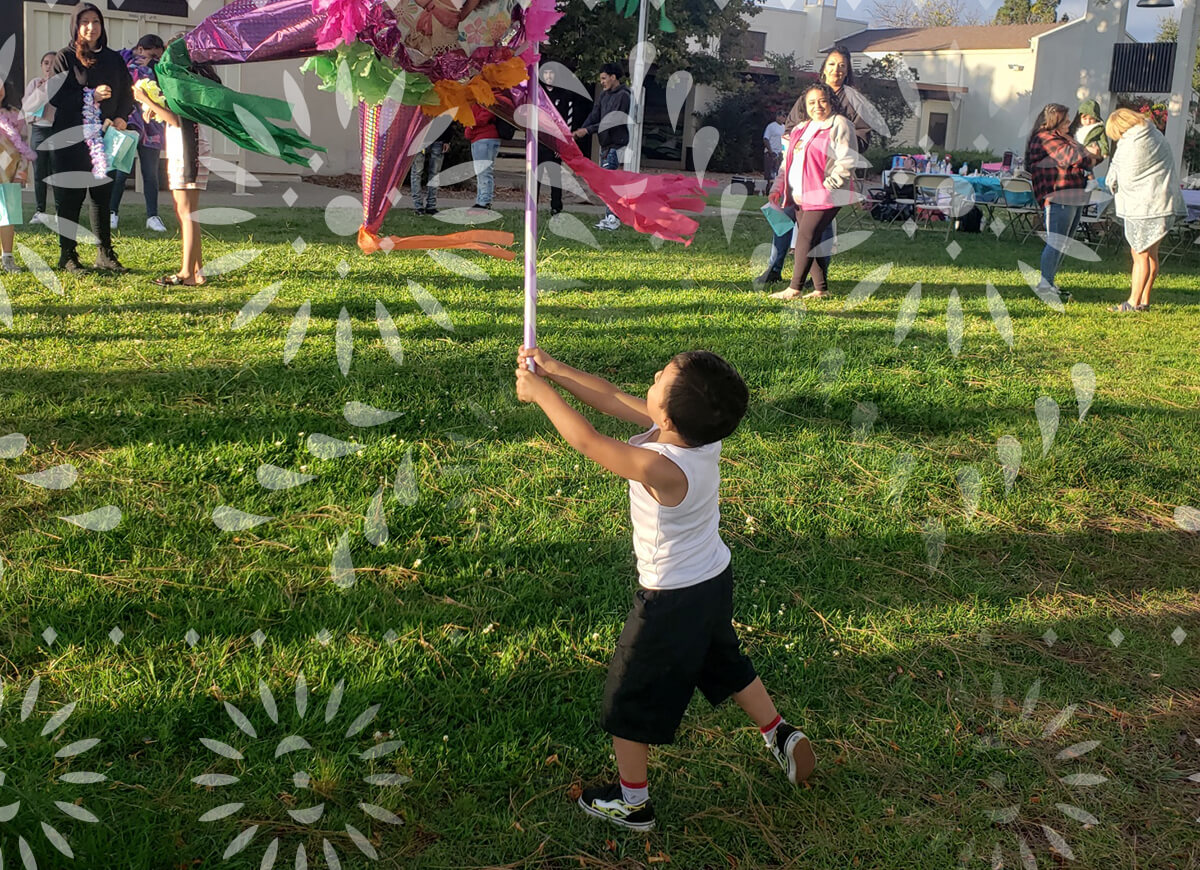 Decorative image of a young child striking a piñata